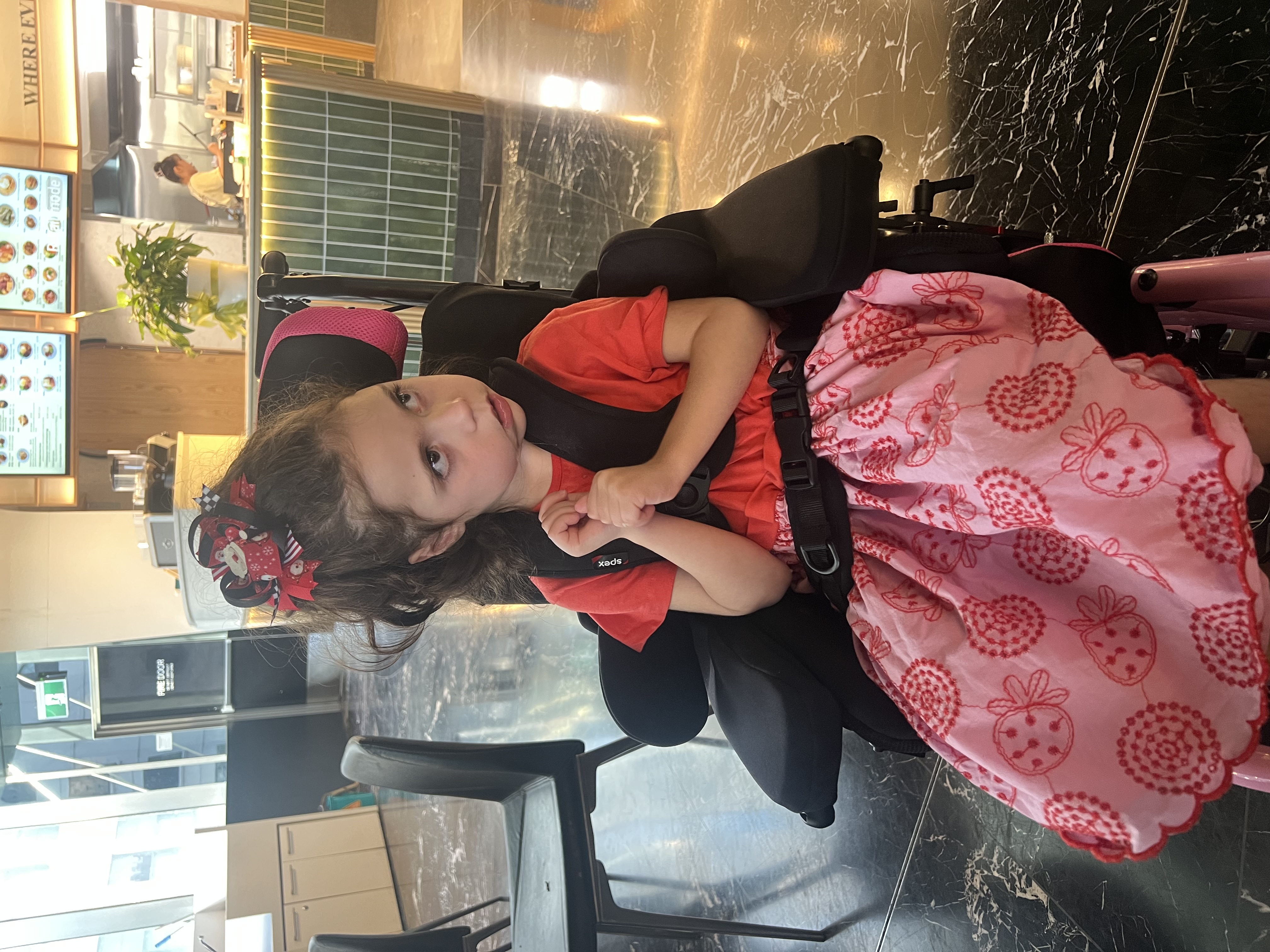 A young child sitting in a wheelchair in a community setting